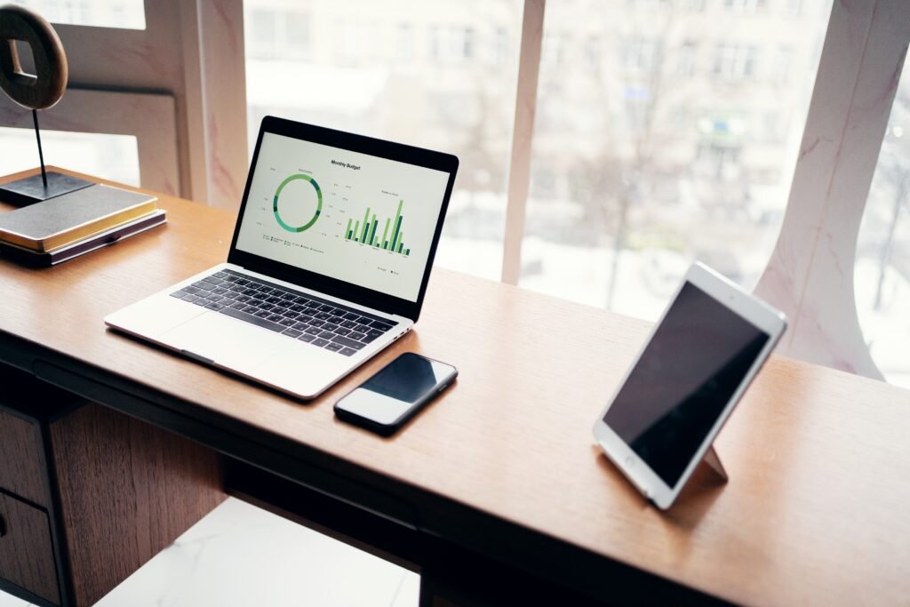 a laptop and cell phone on a desk with customer management system on screen