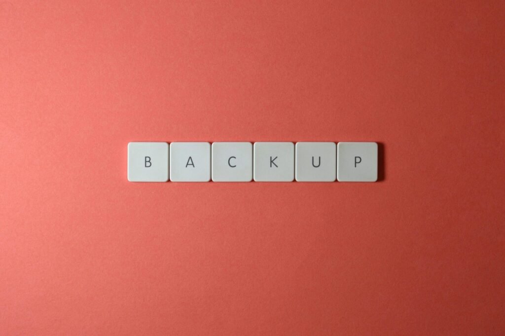 Simple Backup and Recovery Plans Every Small Business Needs 3 Free Close-up of keyboard keys spelling 'BACKUP' placed on a coral-colored surface. Stock Photo
