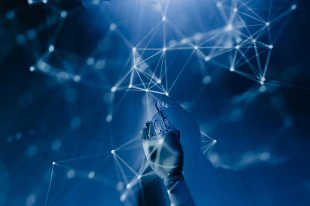 AI Demystified: What to Know About the Current Tools on the Market in 2025 5 Free A robotic hand reaching into a digital network on a blue background, symbolizing AI technology. Stock Photo