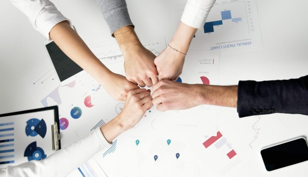 How Smart IT Boosts Employee Morale and Keeps Your Best People 1 Free Colleagues celebrate success with a fist bump over financial charts depicting teamwork and unity. Stock Photo
